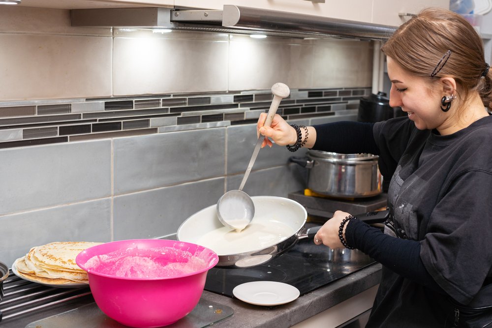 Mujer adolescente cocinando crepes